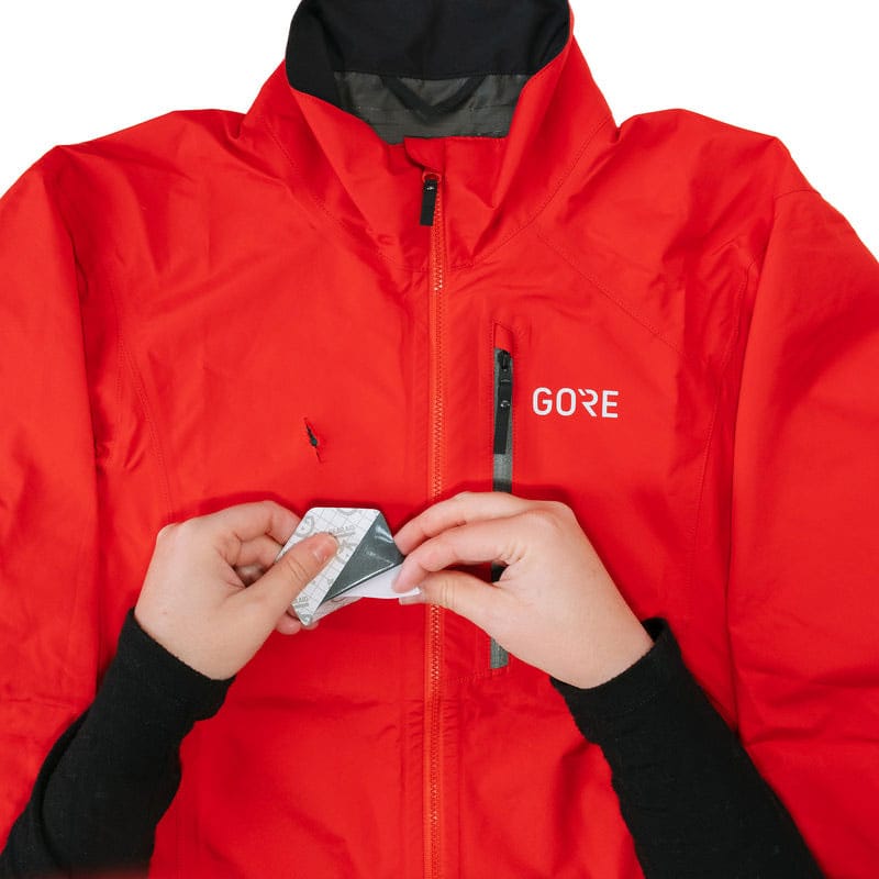 Load image into Gallery viewer, Person wearing a red jacket with 'GORE' branding, holding a card.