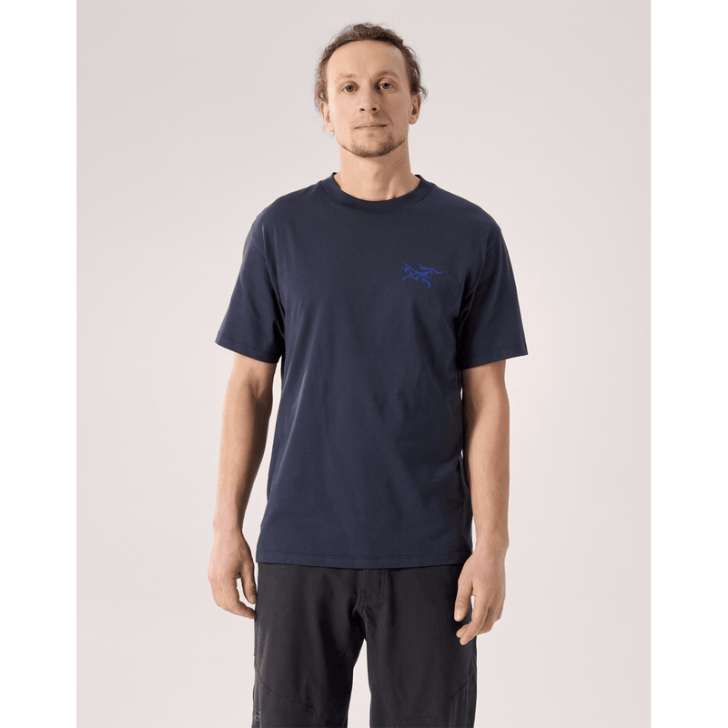 Load image into Gallery viewer, Man wearing a navy blue t-shirt with a logo on a light gray background