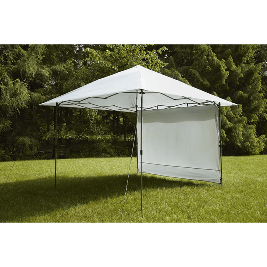 Outdoor canopy tent with side panels set up on grass with trees in the background
