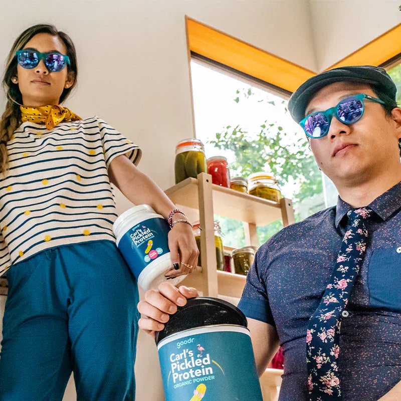 Load image into Gallery viewer, Two people wearing sunglasses holding containers of GoPro'd Pickled Protein.