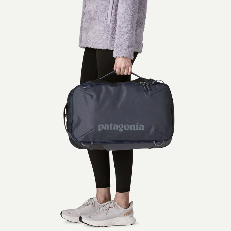 Load image into Gallery viewer, Person holding a navy and grey Patagonia duffel bag on a white background