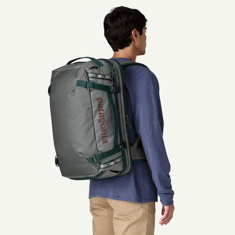 Load image into Gallery viewer, Person wearing a gray backpack with Patagonia branding on a white background