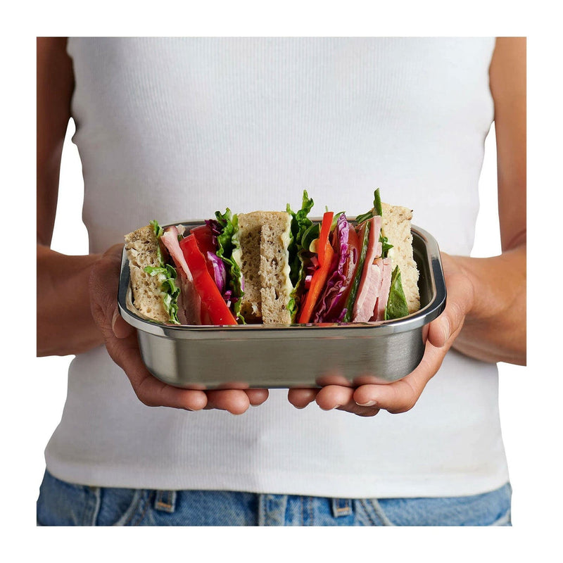 Load image into Gallery viewer, Person holding a metal lunch box with a sandwich filled with vegetables.
