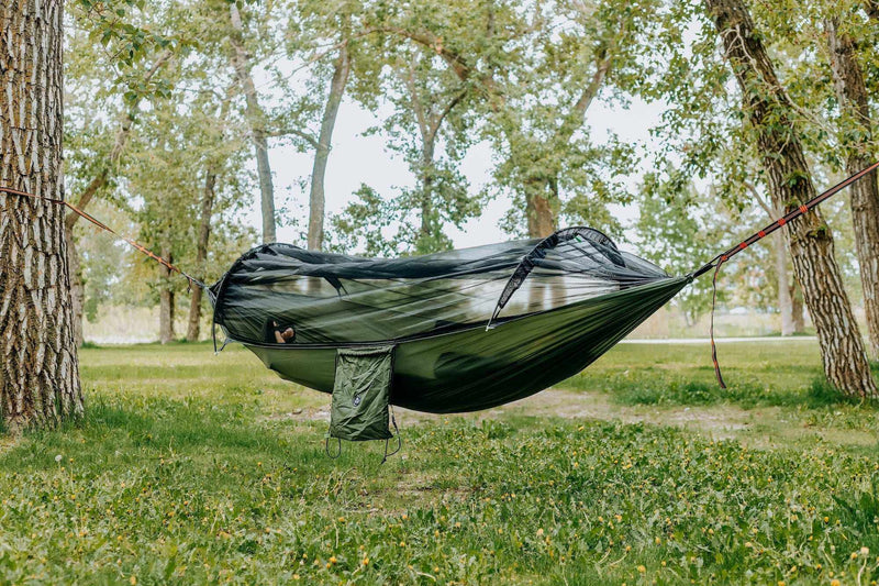 Load image into Gallery viewer, Lightweight hammock with mosquito net in a forest setting for outdoor comfort.