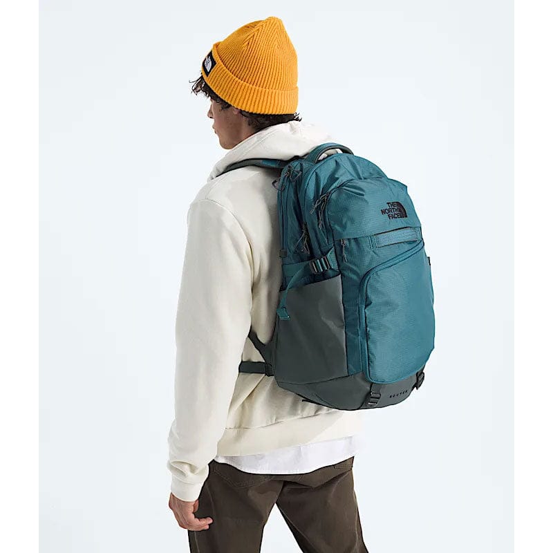 Load image into Gallery viewer, Person wearing a teal backpack with The North Face logo on a white background