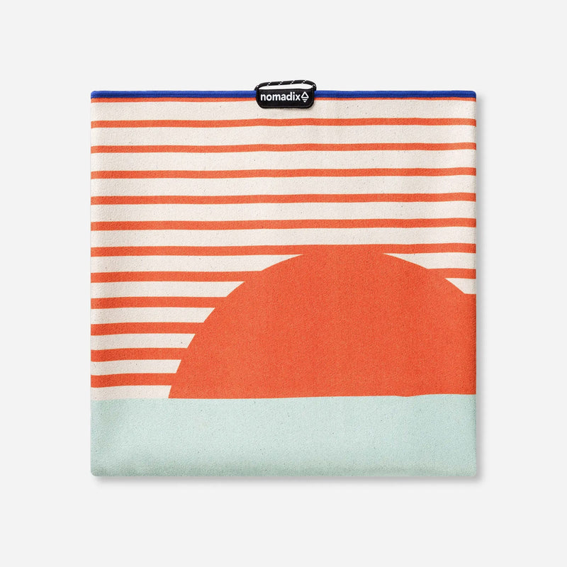 Load image into Gallery viewer, Folded fabric with orange and white stripes and a large orange circle on a light blue background, featuring the brand 'nomadix'.