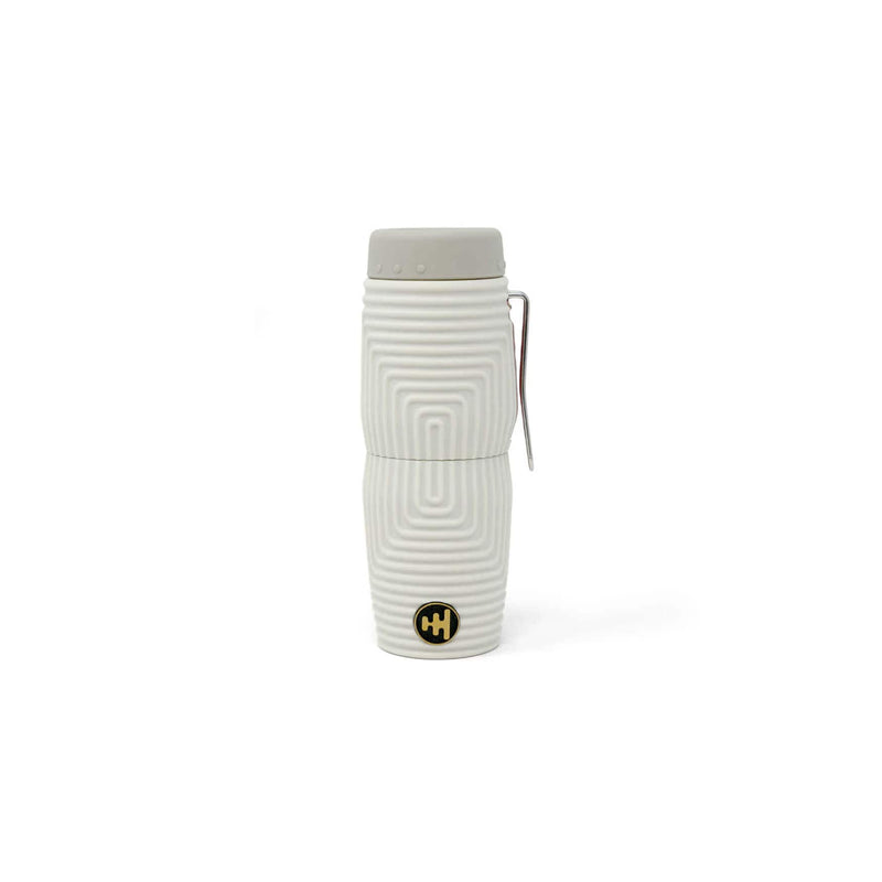Load image into Gallery viewer, A white insulated travel tumbler with a gray lid and a small gold circular logo near the bottom, shown on a plain white background.