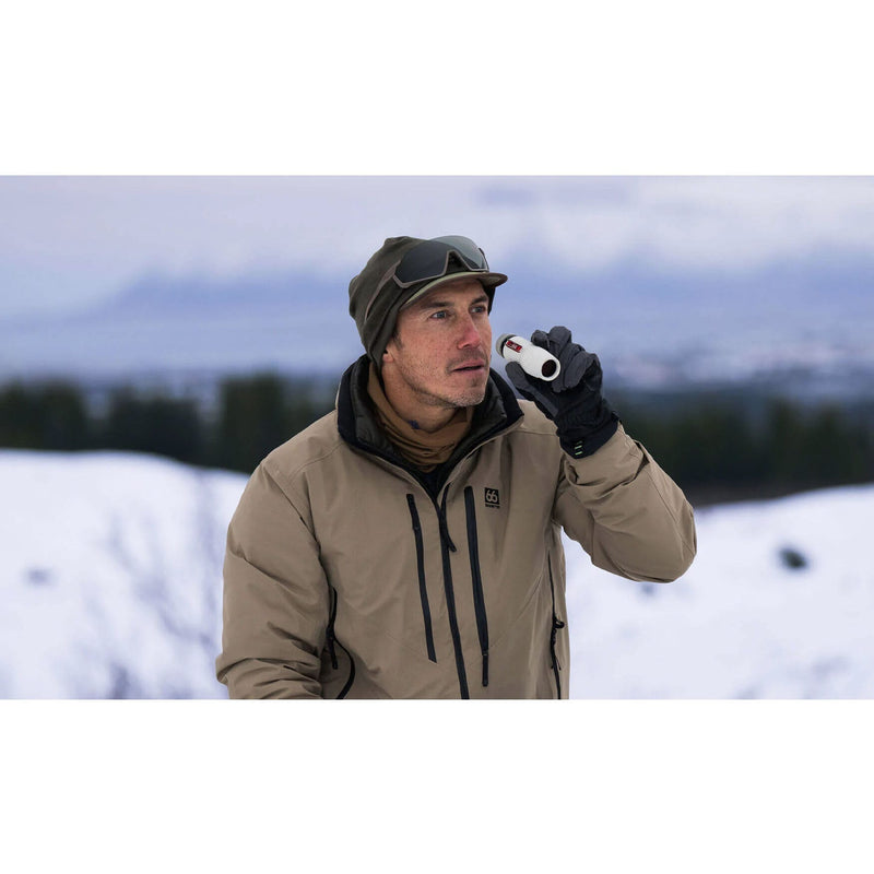 Load image into Gallery viewer, A man wearing a beige outdoor jacket, black gloves, and a dark cap stands in a snowy landscape holding a white binocular.