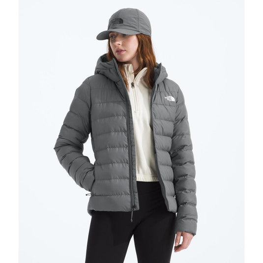 Person wearing a gray puffer jacket and cap on a white background