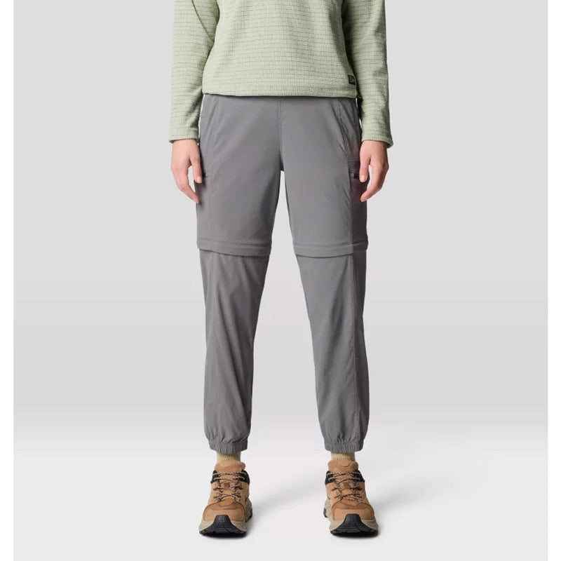Load image into Gallery viewer, A pair of gray Mountain Hardwear women's Dynama convertible utility joggers with a zipper at the lower half for detachable short wear, featuring a wide and low-profile stretch waistband, side entry hand pockets, and secure zip cargo thigh pockets.