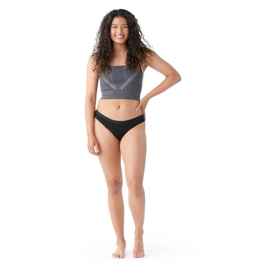 Woman wearing a gray crop top and black bikini bottoms on a white background
