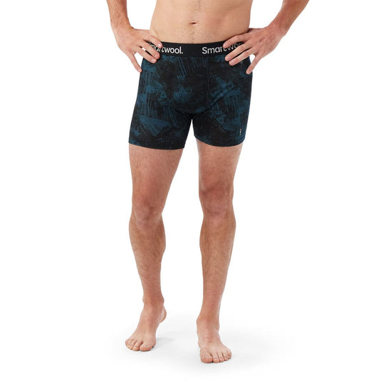 Person wearing black patterned boxer briefs with 'Smartwool' branding on a white background