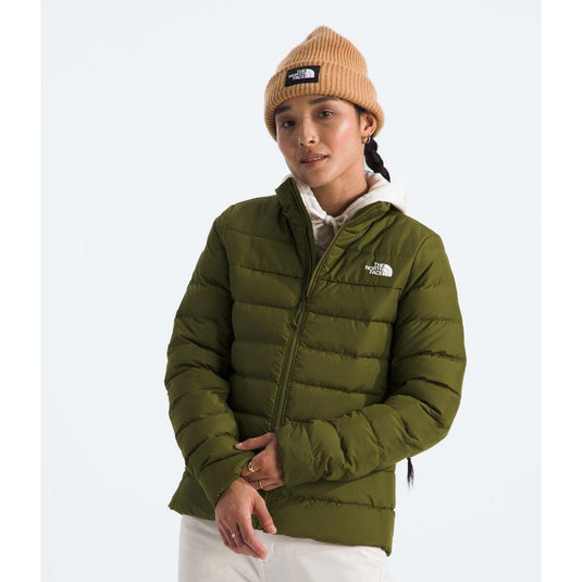 A woman wearing a green The North Face puffer jacket with a beige beanie.