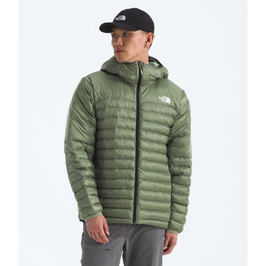 Person wearing a green puffer jacket with a brand logo on a white background