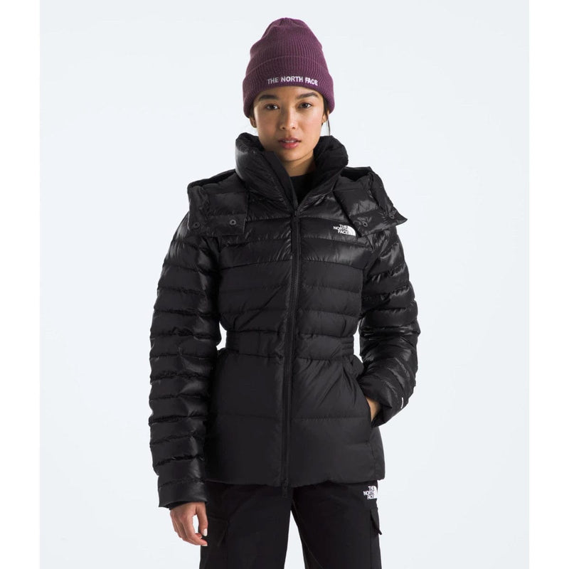 Load image into Gallery viewer, A woman wearing a black The North Face winter jacket with a hood, black pants, and a purple beanie.