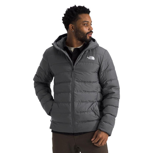 Man wearing a gray puffer jacket with The North Face logo on a white background