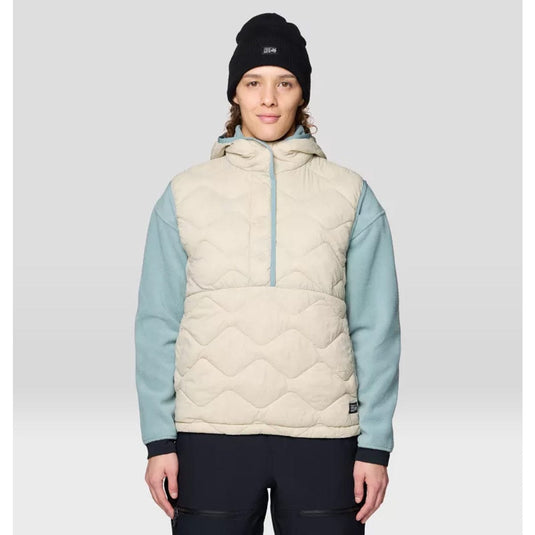 Person wearing a quilted vest with light blue sleeves and a black beanie on a gray background