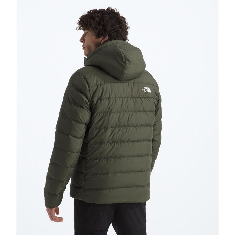 Load image into Gallery viewer, Person wearing a green puffer jacket with a brand logo on a white background