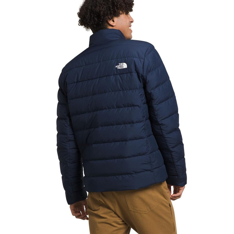 Load image into Gallery viewer, Person wearing a navy blue puffer jacket with The North Face logo on a white background