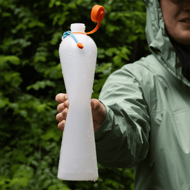 Load image into Gallery viewer, Person holding a white water bottle with an orange cap outdoors