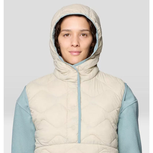 Person wearing a beige quilted vest with a hood against a light gray background
