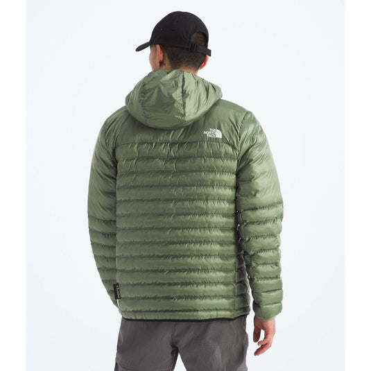 Person wearing a green puffer jacket with a brand logo on a white background