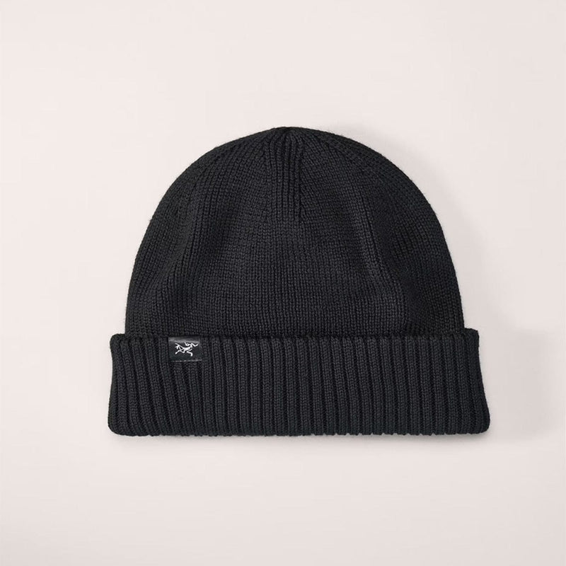 Load image into Gallery viewer, Black knit beanie with a brand logo on a light gray background