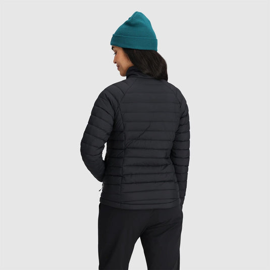 Person wearing a black puffer jacket and teal beanie on a light gray background