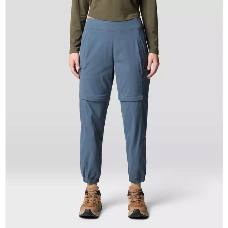 Load image into Gallery viewer, A pair of gray Mountain Hardwear women's Dynama convertible utility joggers with a zipper at the lower half for detachable short wear, featuring a wide and low-profile stretch waistband, side entry hand pockets, and secure zip cargo thigh pockets.