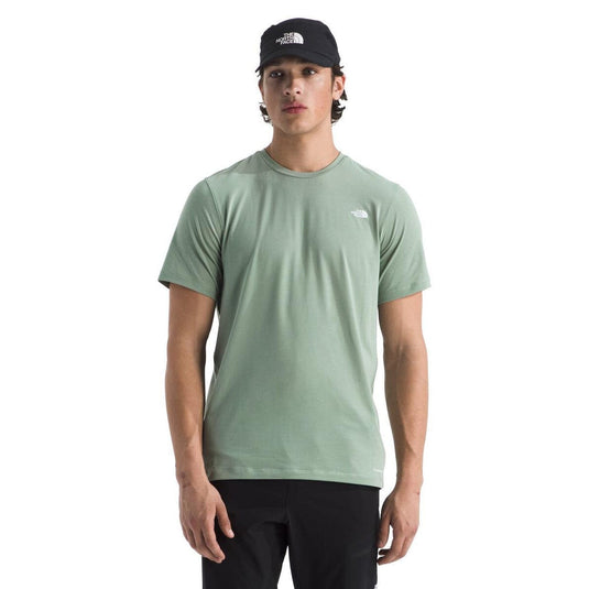 Person wearing a green t-shirt and black cap with a logo on a white background
