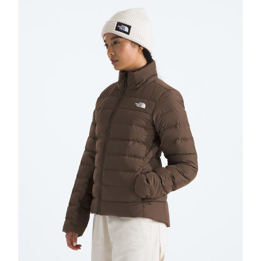 Person wearing a brown puffer jacket and white beanie with The North Face logo on a white background