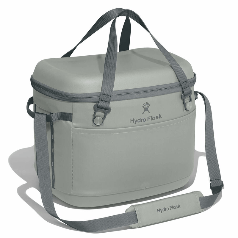 Load image into Gallery viewer, A light gray Hydro Flask insulated cooler bag with dark gray handles, straps, and zipper trim, shown on a white background with its shoulder strap laid out in front.
