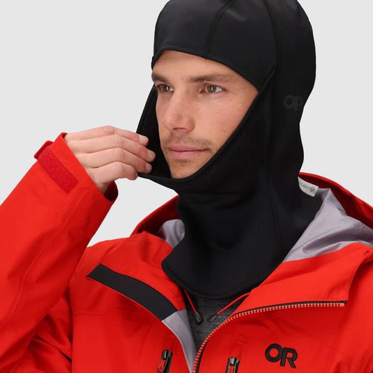 Person wearing a red and gray jacket with a black hood, featuring the OR logo.