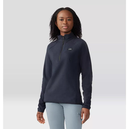 Person wearing a navy blue pullover with a brand logo on a light gray background