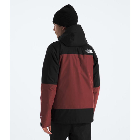 Person wearing a black and red jacket with a visible brand logo on a white background