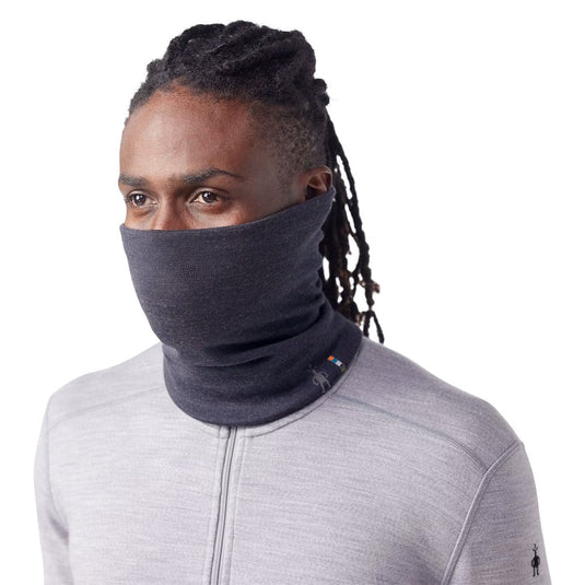 Person wearing a dark gray neck gaiter with a white background