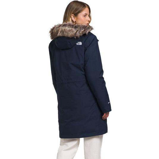 Person wearing a navy blue coat with fur hood on a white background