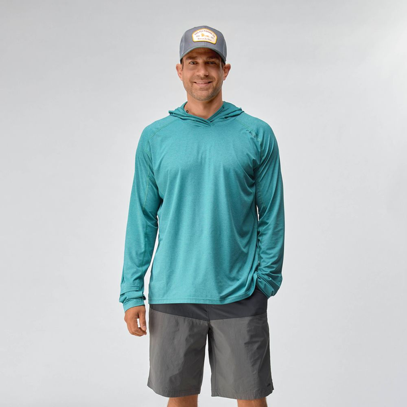 Load image into Gallery viewer, Man wearing a teal long-sleeve shirt, gray shorts, and a cap on a light gray background