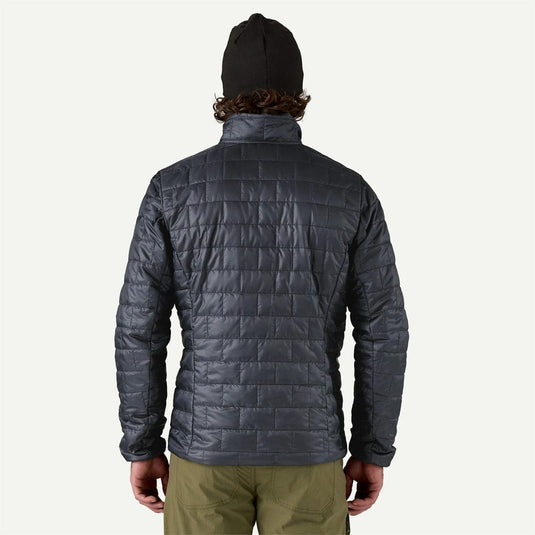 Person wearing a dark gray quilted jacket on a white background