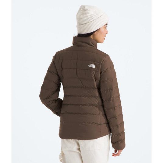 Person wearing a brown puffer jacket with The North Face logo on a white background