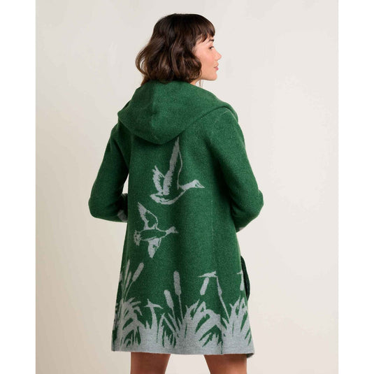 Green coat with white bird and plant pattern worn by a person on a plain background