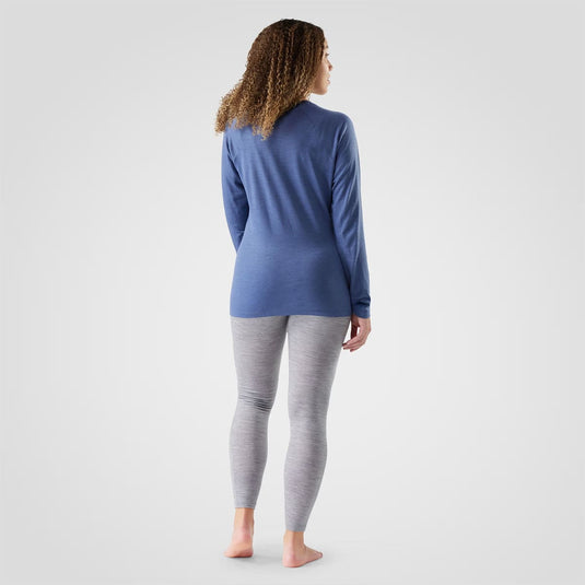 Person wearing a blue long-sleeve top and gray leggings on a white background
