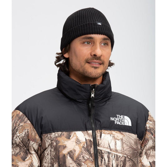 Man wearing a black and camouflage jacket with 'The North Face' logo on a white background