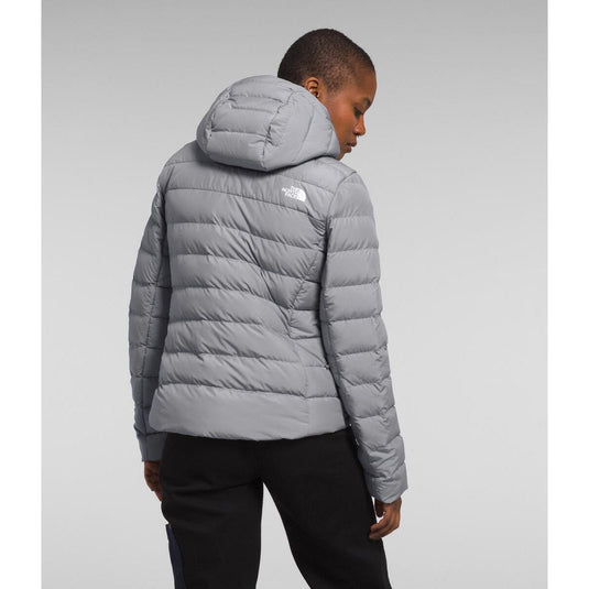 Person wearing a gray puffer jacket with a brand logo on a light gray background