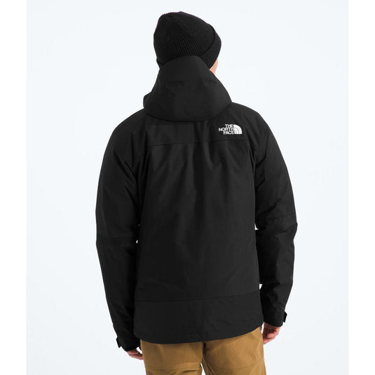 Person wearing a black jacket with a visible brand logo on the back, standing against a white background.