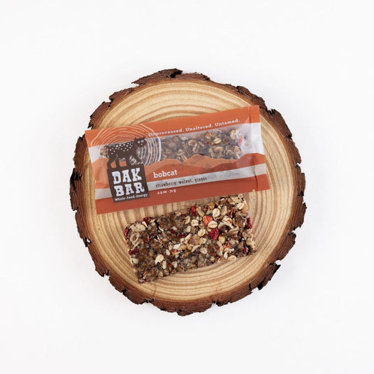 Dak Bar bobcat food on a wooden platform with a white background