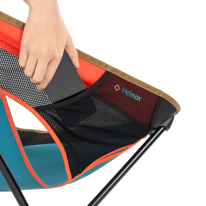 Load image into Gallery viewer, Helinox camping chair with a hand opening the storage compartment on a white background
