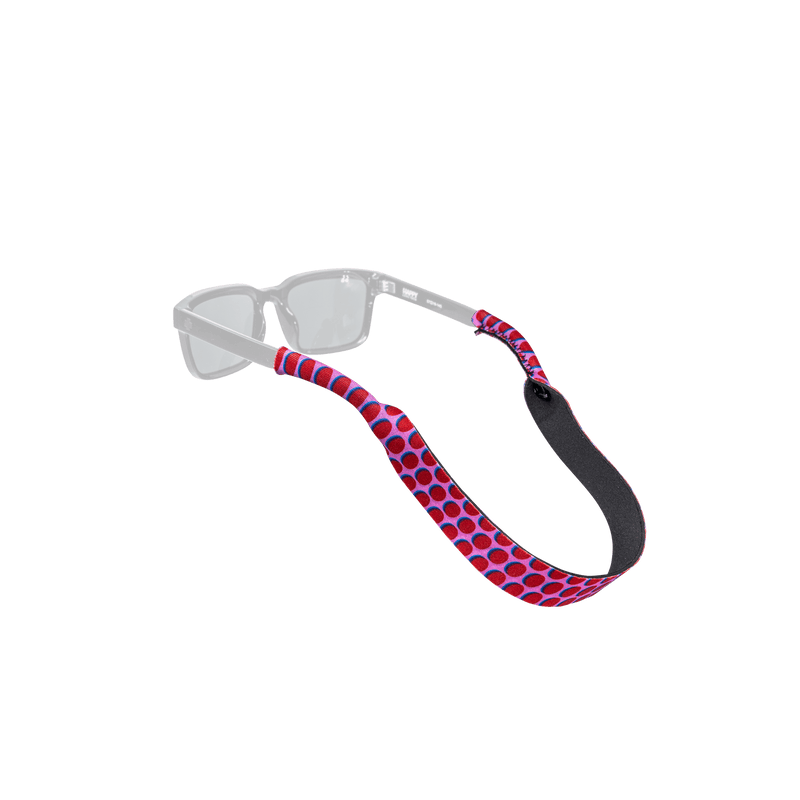 Load image into Gallery viewer, A pair of clear-framed sunglasses with a red and blue polka dot patterned strap, shown against a solid white background.
