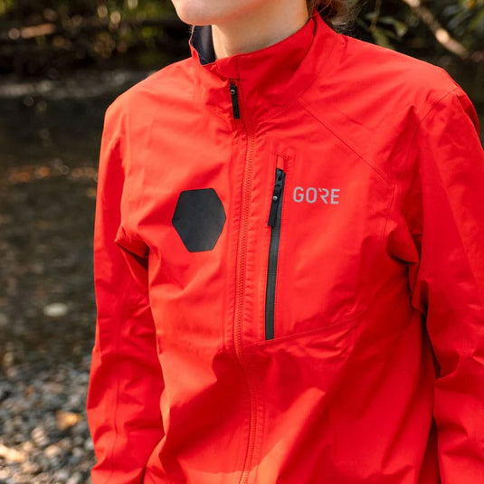 Person wearing a red jacket with GORE branding outdoors.