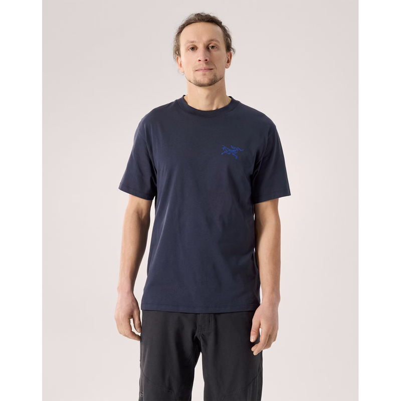 Load image into Gallery viewer, Man wearing a navy blue t-shirt with a logo on a light gray background

